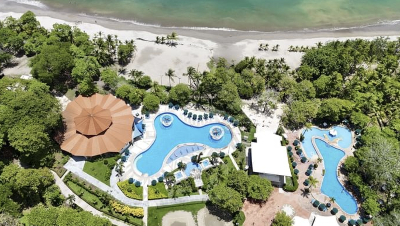 Aerial view of the Punta Leona club: pools surrounded by greenery next to Playa Mantas